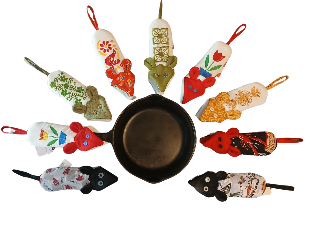 A collection of colorful mouse-shaped kitchen handle potholders arranged in a circle around a black cast iron skillet on a white background.

