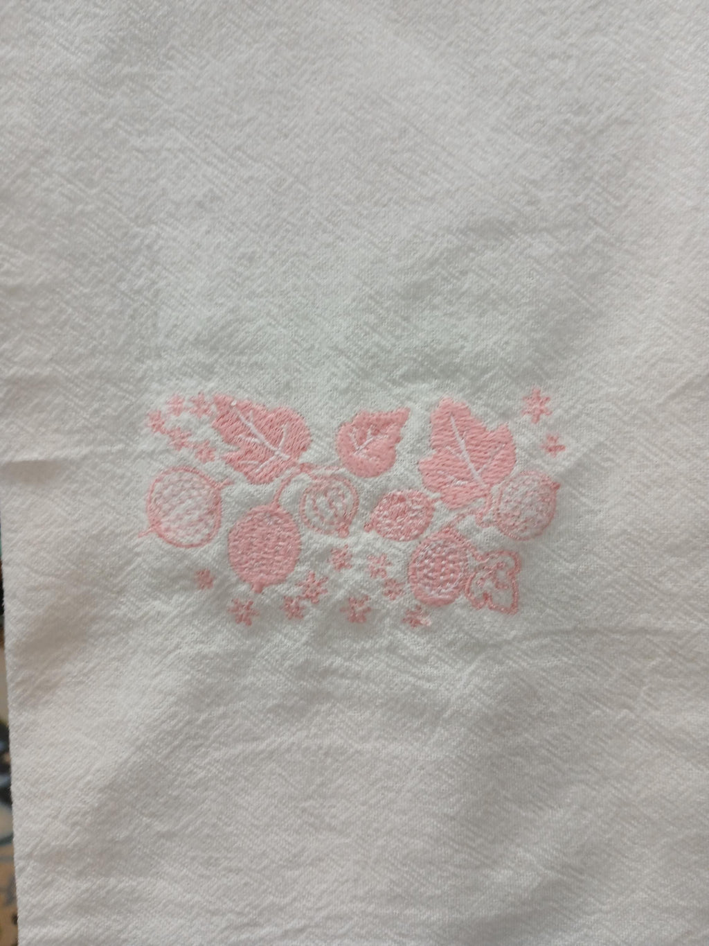 White textured paper towel with a pink floral and leaf pattern printed in the center.